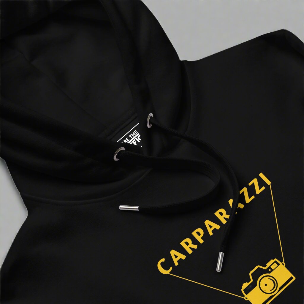 Closeup of black hoodie with carparazzi and camera design in yellow.