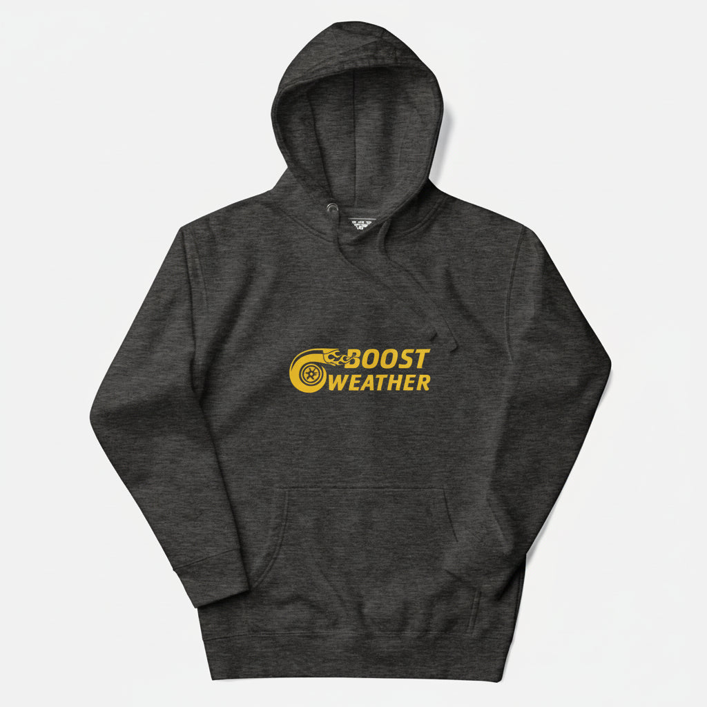 Flat lay of a hoodie in charcoal heather gray with a gold design featuring the phrase Boost Weather and a tire with fire design next to it.